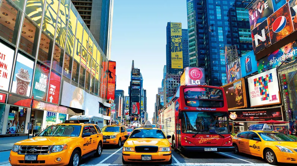 De imponerende reklamesøjler og ikoniske gule taxaer i New York City