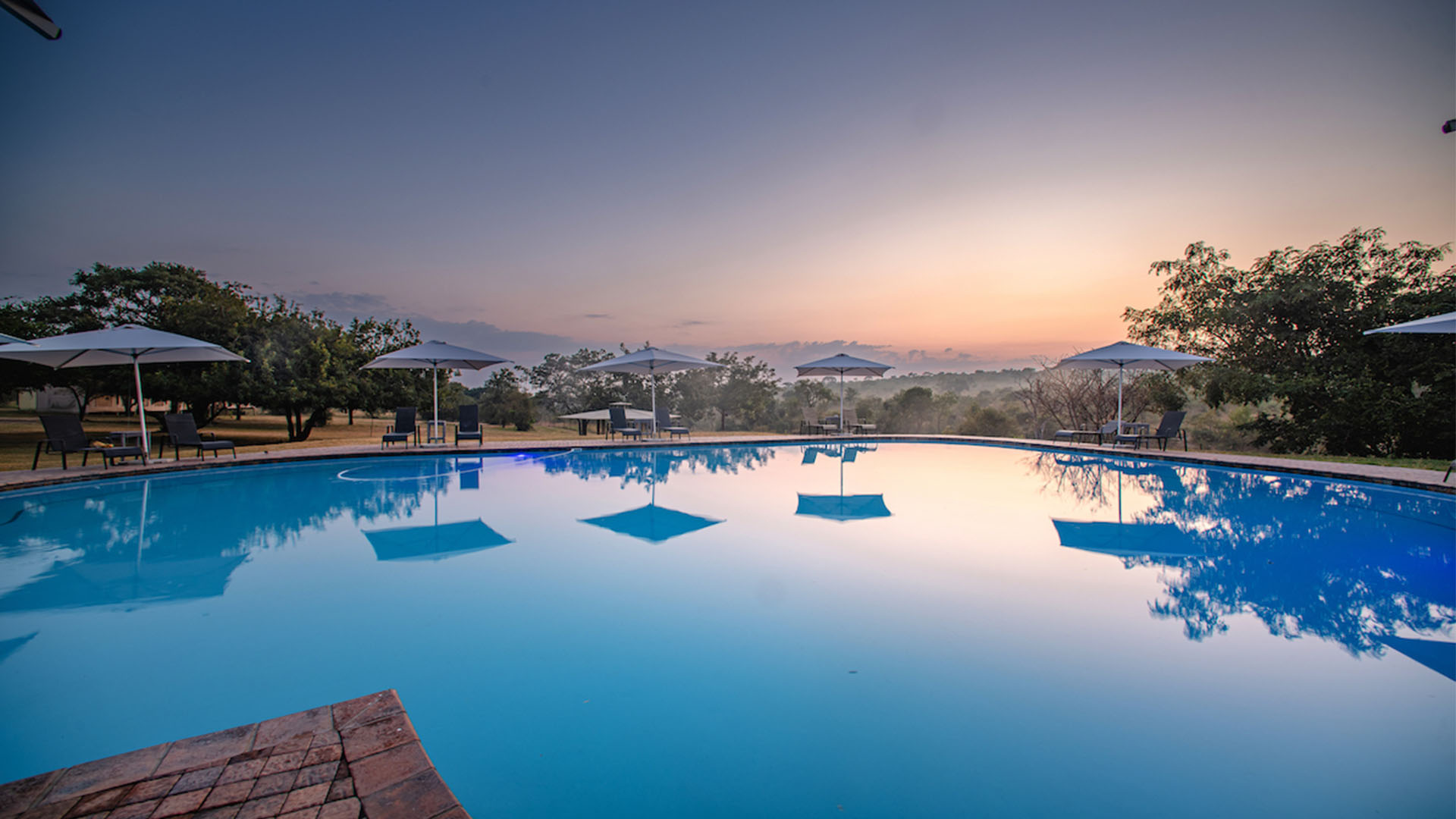 Slap af i den store pool med udsigt over et vandhul, der ofte besøges af flodheste og andre vilde dyr
